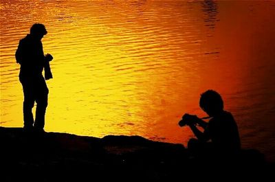 Silhouette of people in swimming pool during sunset