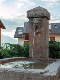 View of fountain by building against sky