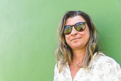 Portrait of young woman wearing sunglasses against black background