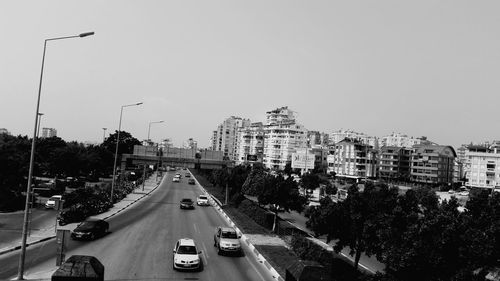 Traffic on road in city against clear sky