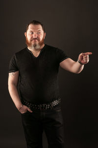 Portrait of young man standing against black background