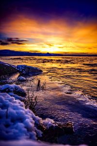 Scenic view of sea against dramatic sky during sunset