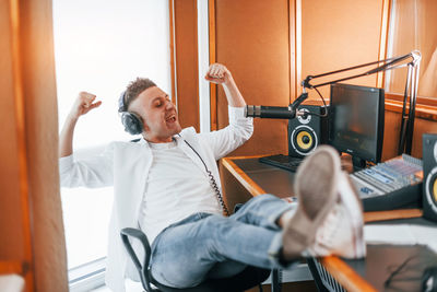 Talks and uses mic. young man is indoors in the radio studio is busy by broadcast.