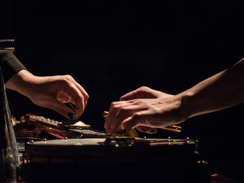 Cropped hands playing music against black background