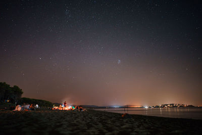 People on beach against sky at night