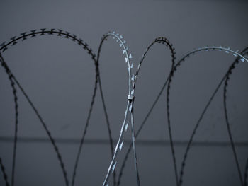 Close-up of barbed wire fence against sky