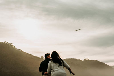 Rear view of couple kissing against sky