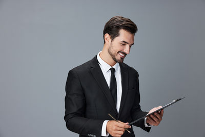 Young man using mobile phone against gray background