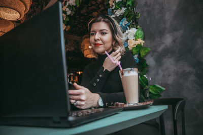 Young woman using mobile phone while sitting on table