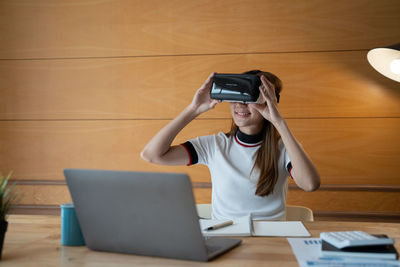 Woman using virtual reality headset on table at home