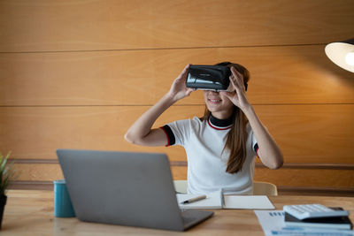 Woman using mobile phone while sitting on table