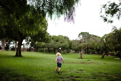 Two year old running through park with back to camera