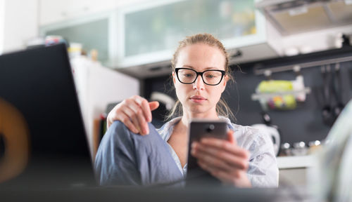 Business woman using smart phone while sitting at home