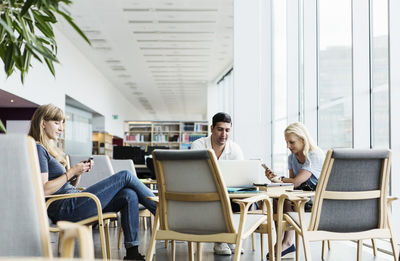 University students using technologies at table in library