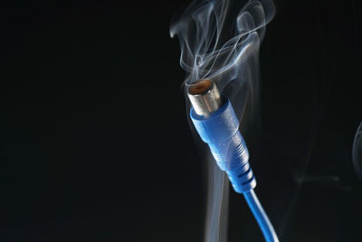 Close-up of emitting smoke against black background