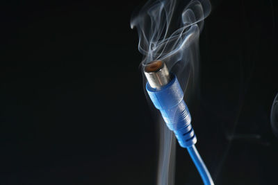 Close-up of cable with smoke in darkroom