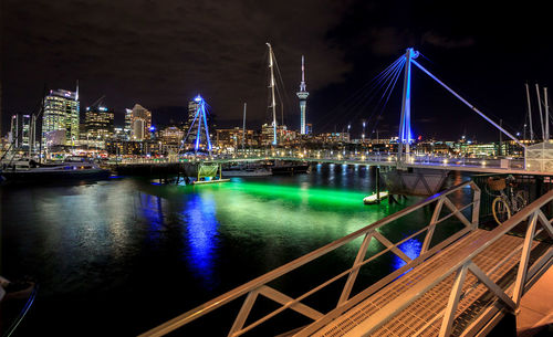 Illuminated bridge over river with buildings in background