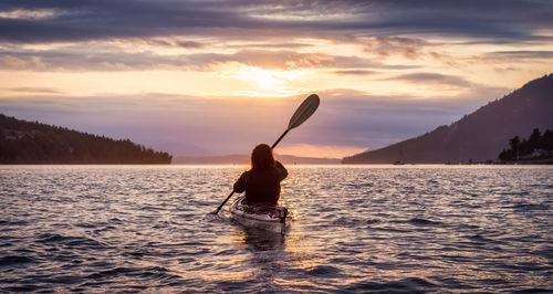 Silhouette person in sea against sky during sunset