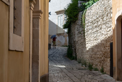 A street in the ancient district of ragusa ibla and a tourist with an umbrella