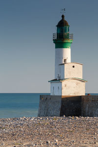 Lighthouse by sea against sky