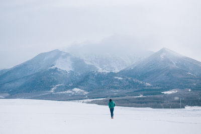 Rear view of woman walking on snowcapped mountain