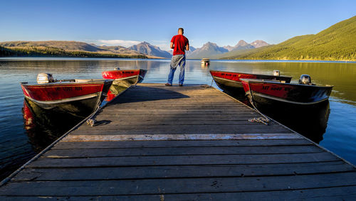 Rear view of man standing on pier at mcdonald lake