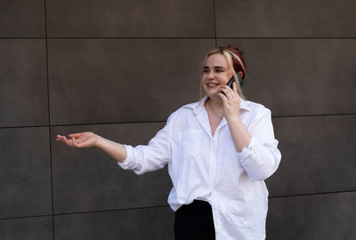 Real young 20 yo plus size girl talking on cell phone, modern building on background. smiling with