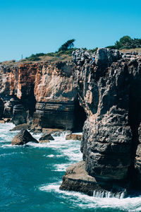 Rock formations by sea against clear sky