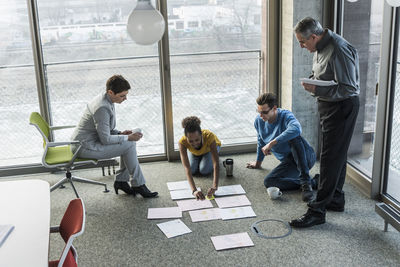 Businesspeople looking at documents on office floor