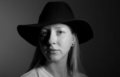 Portrait of woman wearing hat against black background