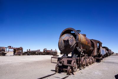 Abandoned train on land against clear blue sky