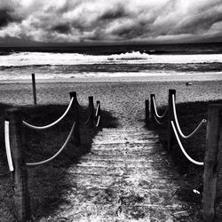 Pier on sea against cloudy sky