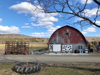 Barn on field by building against sky