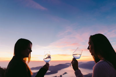 Close-up of a woman drinking water at sunset