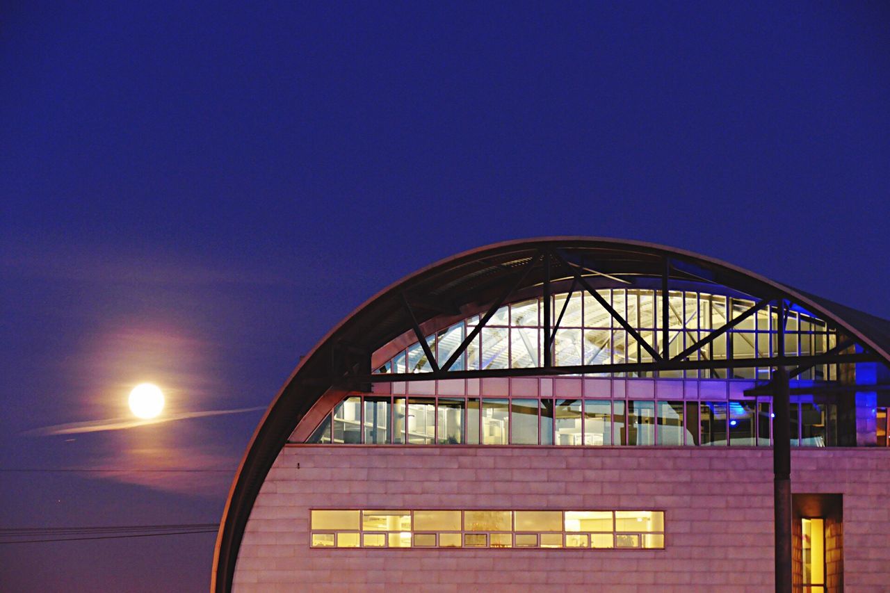 built structure, architecture, low angle view, blue, clear sky, building exterior, copy space, sky, railing, geometric shape, circle, no people, outdoors, sunset, sunlight, building, pattern, illuminated, metal, day