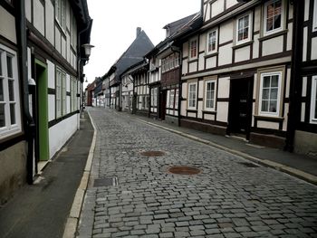 Cobblestone street in city against clear sky