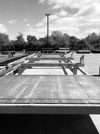 Empty benches in park against sky