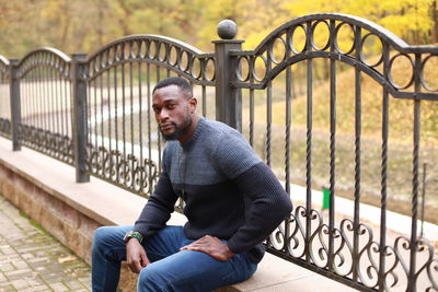 Young man sitting on railing