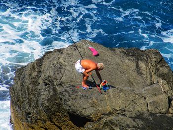 High angle view of man on rock in sea