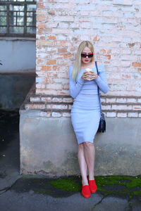 Beautiful woman standing by wall