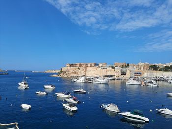 Sailboats moored in sea against blue sky