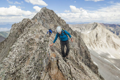 Women climb narrow ridge on capitol peak, elk mountains, colorado