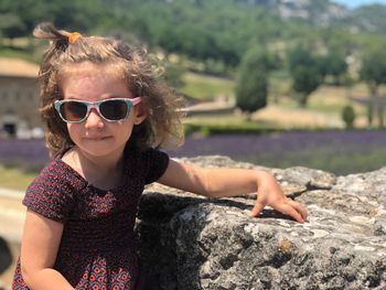 Portrait of girl wearing sunglasses while standing against rock