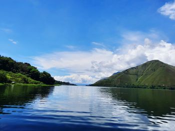 Scenic view of lake by mountains against sky