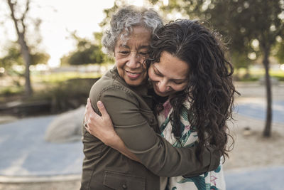 Happy mother embracing daughter at park