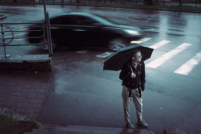 Full length of man standing on wet street