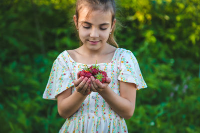 Smiling girl holding strawberries in hands cupped