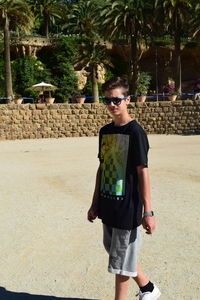 Young man wearing sunglasses standing against trees