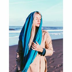 Young woman standing by sea against sky