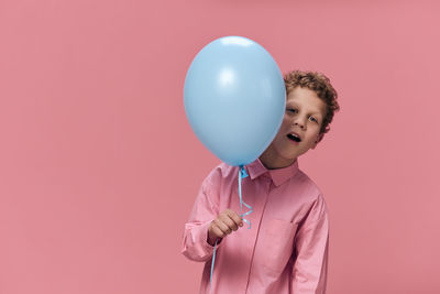 Midsection of woman with balloons against pink background